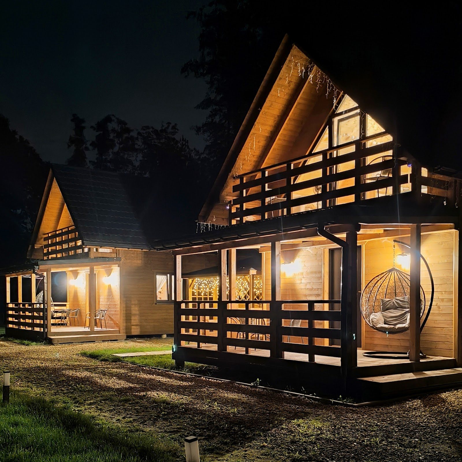 Domki Las Lorien po zmroku, girlandy światła na tarasach i fotel wiszący