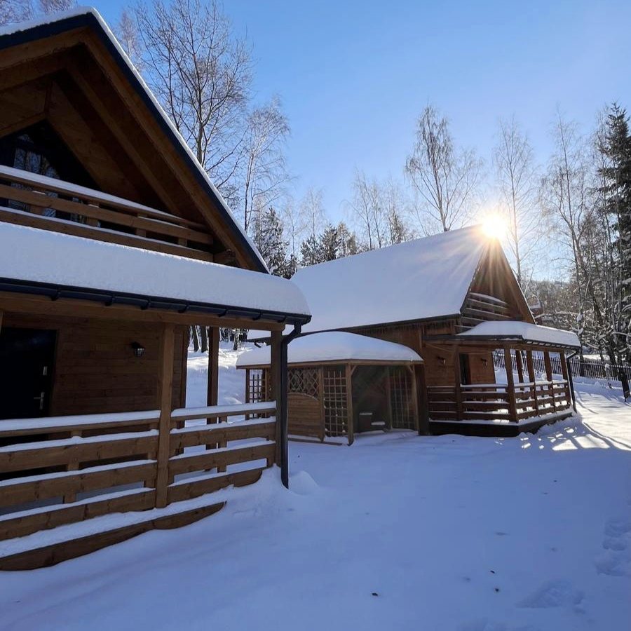 Domki i altana z jacuzzi pod śniegiem w zimowe słoneczne popołudnie